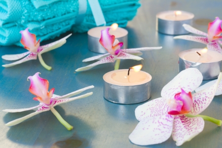 burning candles and orchid flowers on blue tableの写真素材