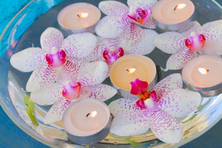 spa therapy with burning  candles and  floating orchid flowers close upの写真素材