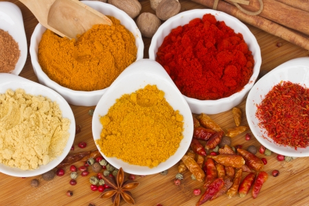 colorful plates  of curry, cucrma and red pepper with seeds of anise and nutmeg on wooden tableの写真素材