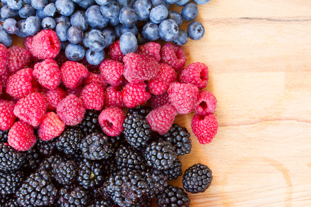 ripe of fresh berries on wooden table - blackberry, raspberry and blueberryの写真素材