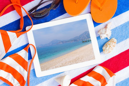 tablet on  towel with sunbathing accessories with seascape on screenの写真素材