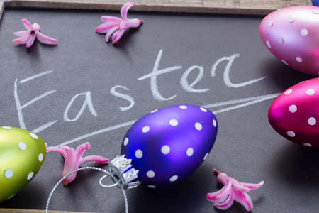 White easter letters on black chalkboard with colorful eggsの写真素材