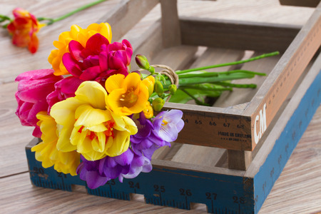 bouquet of pink tulips,  yellow daffodils and freesea flowers in wooden crateの写真素材