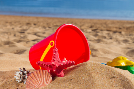 bucjket with seashells  in sand on sea shore at sunny summer dayの写真素材