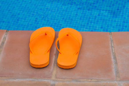 orange flip flops fleft on pool edge