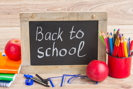 black chalk board with back to school and school supplies on table