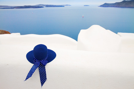 blue straw sun hat against volcano caldera, beautiful details of Santorini island, Greeceの写真素材