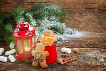two  Gingerbread men with mug of hot chocolate and glowing lantern on wooden background