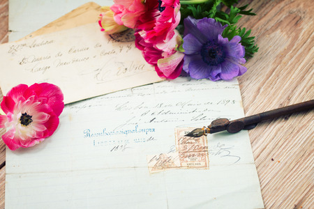old retro golden quill pen and antique testament  with anemone flowers