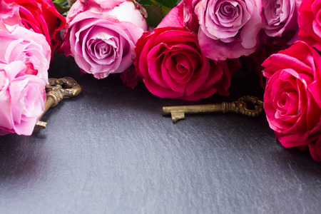 Keys with fresh pink roses  as a symbol of love and copy space on blackの写真素材