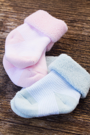 baby pink and blue socks on wooden backgroundの写真素材