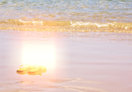 orange flip flops by the blue  sea shore in hot summer dayの写真素材