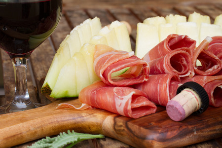 spanish tapas  - slices of cured pork ham jamon with melon and red wineの写真素材