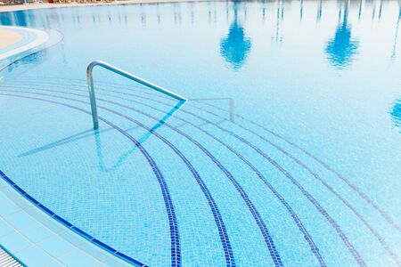 blue swimming pool with  reflections of palm trees