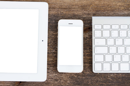 Top view office workplace -  tablet, keyboard and phone on wooden background, copy space on screenの写真素材