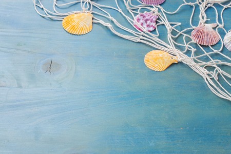 fishing net with sea shells on blue wood with copy spaceの写真素材