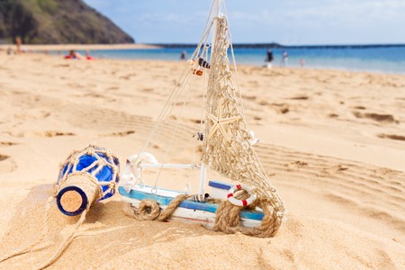 wooden model boat at ocean sandy coast at sunny summer dayの写真素材