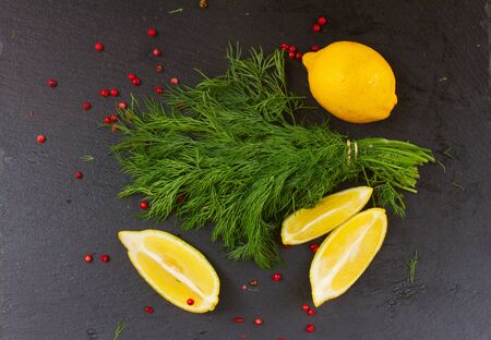 Fresh green dill with red pepper spice and lemons on black boardの写真素材