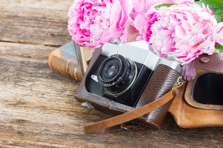retro  photo camera with books and fresh pink peony flowersの写真素材