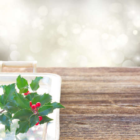 Holly branch with green leaves and red berries on wood, copy space on gray bokeh backgroundの写真素材