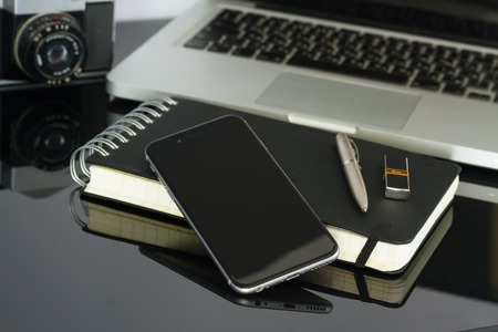 Office glass desk table with phone, laptop and supplies