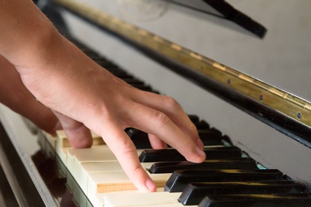Someones two hands playing music on piano keysの写真素材