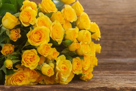 bunch of fresh yellow roses  close up  on wooden backgroundの写真素材