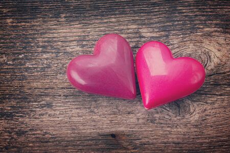 couple of pink  hearts laying together on wooden background, retro tonedの写真素材