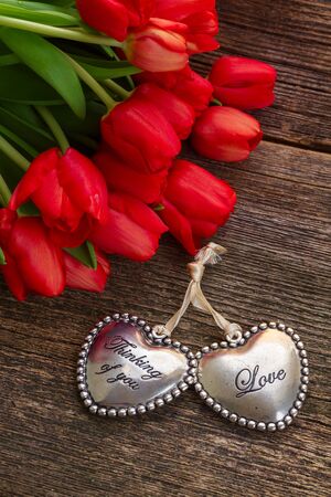 Lover hearts with red tulip flowers on wood