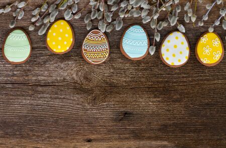 Easter border with eggs cookies and catkins on wood