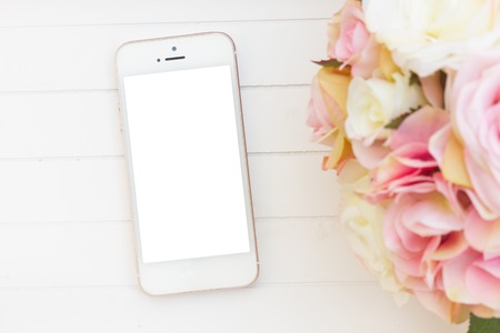styled white wooden desktop  with modern phone  and flowersの写真素材