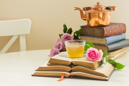 Cup of tee in glass cup  with teapot, old books and rose flowersの写真素材
