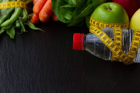 Healthy raw food and  water  with measuring tape, copy space  on tableの写真素材