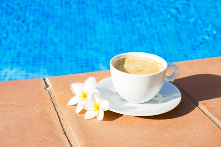 white cup of coffee near pool waterの写真素材