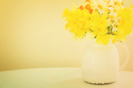 Fresh spring daffodils in clay white pot on table, retro tonedの写真素材