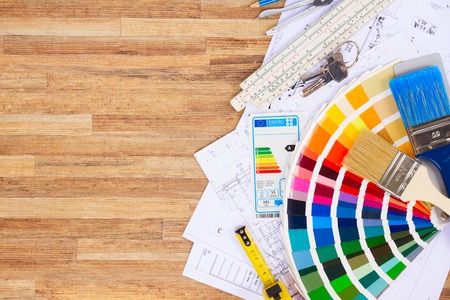 Interior designer's working table with energy rating chart, architectural plan of the house, color palette and brushes, copy space on wooden desktopの写真素材