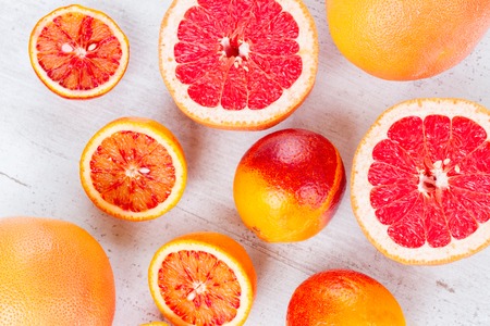 Variety of whole an cut citruses on white tableの写真素材