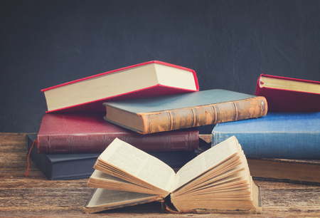 Open old book with pile of closed on wooden bookshelf , retro tonedの写真素材