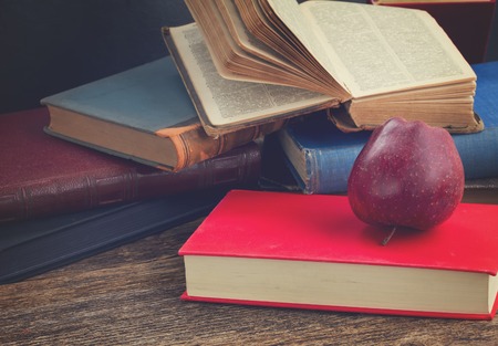 Pile of books with apple on wooden bookshelf, retro tonedの写真素材