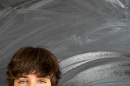 Eyes of teenager boy against blackboard background