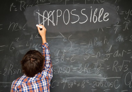 boy putting a cross over impossible on blackboard with math calculationsの写真素材