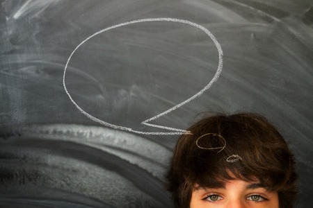 Eyes of teenager boy against blackboard background with speech bubbleの写真素材