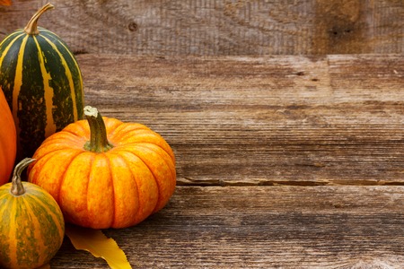 pile of orange and green pumpkins on wooden table background with copy spaceの写真素材