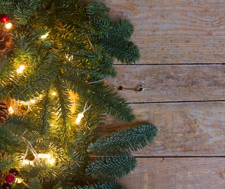 Christmas border with fir tree and lights on old wooden planks backgroundの写真素材