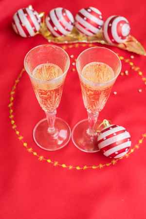 Christmas table with red cloth and decorations with two glasses of champagneの写真素材