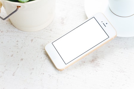Mock up styled flat lay white hight key scene with white phone, copy space on blank screenの写真素材