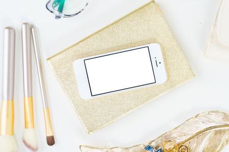 Phone with golden woman accessories mock up flat lay styled scene, top view, copy space on empty screen backgroundの写真素材
