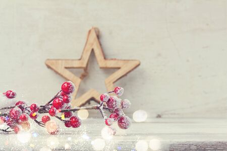 red an white christmas - twig with berries and star on aged wooden background, retro tonedの写真素材