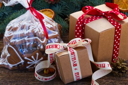 christmas gingerbread cookies in transparent bag with fir tree and gift boxes on wooden table close...