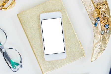 Phone with golden woman accessories and glasses mock up flat lay styled scene, top view, copy space on empty screen backgroundの写真素材